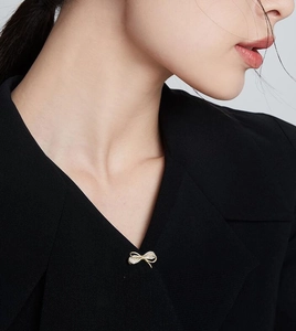Détail d'une broche nœud dorée étincelante avec zircons sur un revers de costume noir