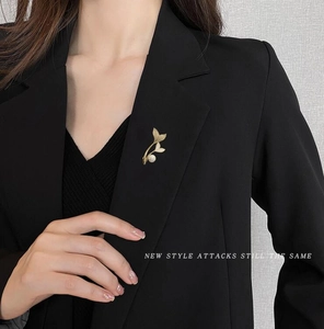 Close-up of golden fishtail pearl brooch on a black suit lapel for elegant styling