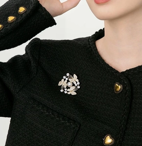 Close-up of butterfly pearl brooch with sparkling crystals on black tweed coat