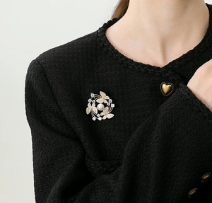Detail of elegant gold butterfly brooch with pearls and zircon on black tweed jacket