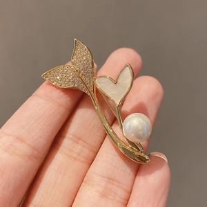 Macro shot of fishtail pearl brooch with gold plating and sparkling rhinestones