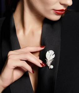 Détail d'une broche plume avec zircon, nacre et perle blanche sur le revers d'un costume