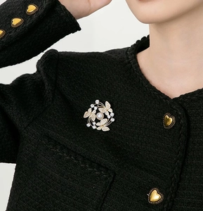 Close-up of pearl butterfly brooch with crystals on a black tweed blazer jacket