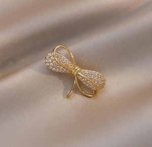 Vue détaillée d'une broche nœud dorée avec strass sur tissu en satin champagne