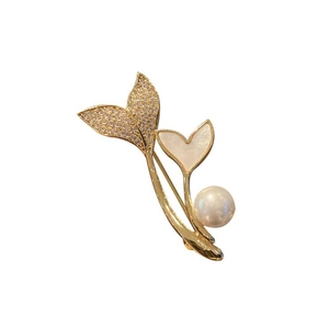 Detailed close-up of pearl brooch with gold leaf design and sparkling diamond accents