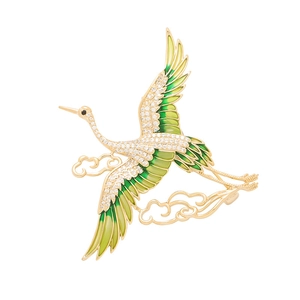 Detailed view of crane brooch with green enamel wings and white zircon inlay on gold base