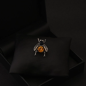 Macro view of vintage bee brooch with amber gemstone on black velvet jewelry box