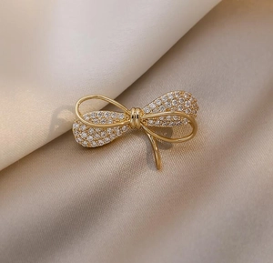 Vue macro d'une broche noeud dorée avec cristaux sur un fond en soie champagne