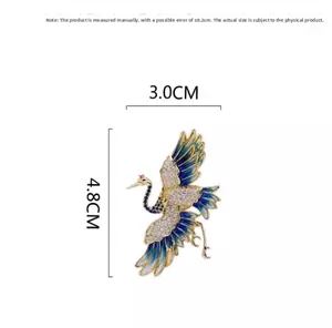 Dettaglio spilla gru con ali in smalto e strass con indicazione delle dimensioni di 4,8 x 3 cm