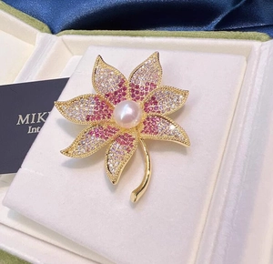 Gros plan détaillé d'une broche feuille d'érable avec cristaux roses et perle blanche