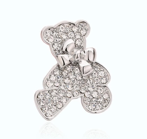 Vue détaillée d'une broche ours argentée ornée de strass brillants et d'un petit noeud