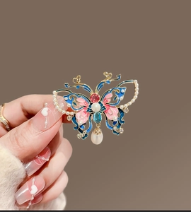 Détail de broche papillon en émail bleu et rose avec monture dorée et perles