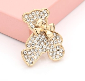 Détail d'une broche en forme d'ours doré étincelant avec des strass et un petit nœud papillon