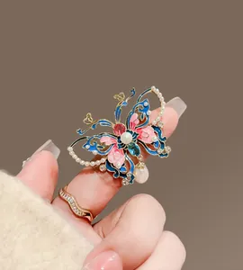 Détail de la broche papillon en émail avec perles et pendentif goutte élégant