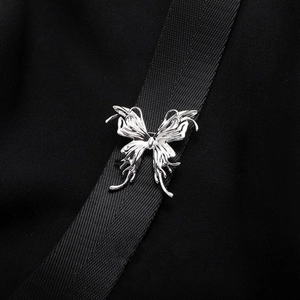 Detailed view of silver butterfly brooch with liquid metal texture on black fabric