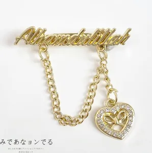 Detailed view of Alhamdulillah letter brooch with gold chain and rhinestone heart pendant