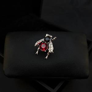 Macro shot of vintage bee brooch with red faceted gemstone and sparkling rhinestone wings