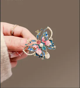 Détail d'une broche papillon en émail avec de grandes perles rondes et en forme de larme
