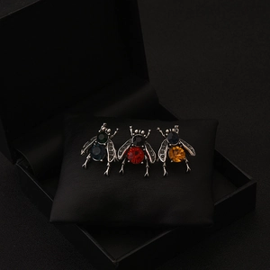 Set of three vintage bee brooches with blue, red, and amber crystals on black leather