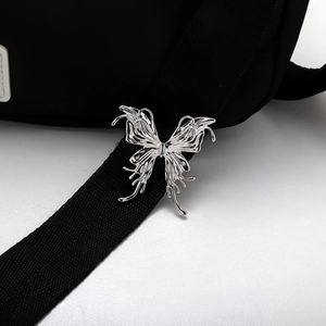 Detailed close-up of liquid metal style silver butterfly brooch on black fabric
