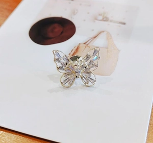 Détail macro d'une broche papillon avec ailes évidées et cristaux de zircone incrustés