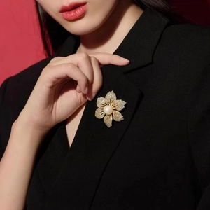 Detailaufnahme einer Blumenbrosche mit Zirkonia und Perle auf einem schwarzen Blazer revers