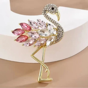 Squisita spilla a fenicottero dorata con cristalli rosa e strass su uno sfondo neutro