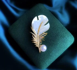 Détail d'une broche plume scintillante avec nacre, zircons et une grande perle ronde