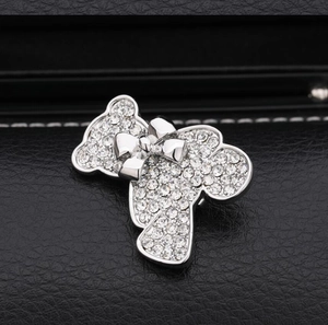 Détail macro d'une broche ours en peluche avec rangées de strass clairs et nœud argenté