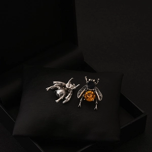 Macro shot of vintage bee earrings with amber and blue gemstones on black velvet pad