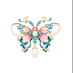 Détail de la broche papillon en émail avec placage à l'or et pendentif perle goutte