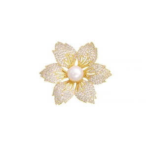 Eleganter goldener Blumen-Brosche mit weißen Perlen und funkelnden Kristallblättern auf Weiß