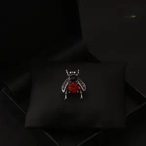 Macro detail of vintage silver bee brooch with red ruby crystal and black rhinestone inlay