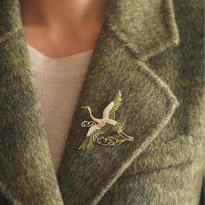 Elegant Chinese crane and cloud brooch pinned on a green wool coat lapel