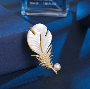 Vue détaillée d'une broche plume de luxe avec zircons blancs, perle et dorure