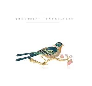 Detail of green enamel bird brooch with sparkling rhinestones and white pearls