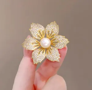 Detail der Blumenbrosche mit funkelnden Kristallen und einer großen zentralen Perle