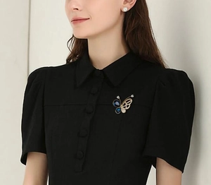 Détail d'une broche papillon élégante avec pierres bleues sur une robe noire