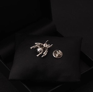 Macro detail of a vintage silver bee brooch with intricate textures on black velvet