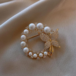 Details einer eleganten Goldbrosche mit weißen Perlen und funkelndem Diamant-Schmetterling