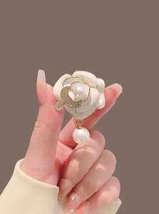 Détail d'une broche camélia avec pétales blancs, croissant en zircon et perle suspendue