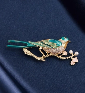 Detail of vintage enamel magpie brooch with shimmering crystals and white pearls on branch