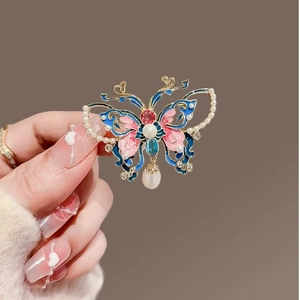 Élégante broche papillon en émail coloré avec perles sur une base dorée ajourée