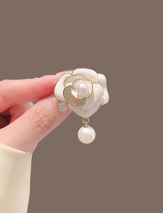 Détail de la broche camélia avec pétales en émail blanc, perle et perle dorée pendante