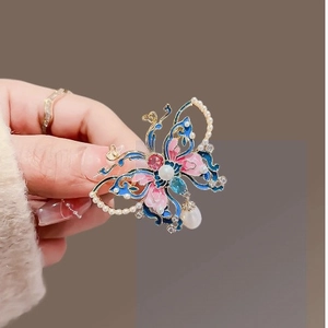Broche papillon luxueuse en émail avec ailes bleues, perles blanches et pierres rouges