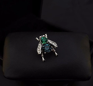 Macro shot of bee brooch with green and blue gemstones and sparkling white crystals