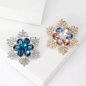 Elegant snowflake brooch set with colorful teardrop crystals on white geometric stand