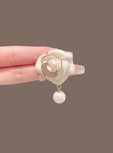 Détails de la broche fleur de camélia avec bords dorés et une perle en forme de goutte