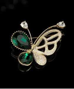 Vue détaillée d'une broche papillon dorée avec gemmes vertes et cristaux étincelants