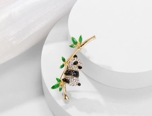 Detailed close-up of a panda brooch with sparkling rhinestones on green enamel bamboo leaves